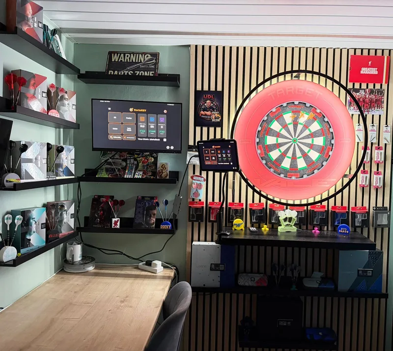A dedicated darts room with a red-lit board, a tablet mounted beside it and DartsKEY on a monitor
