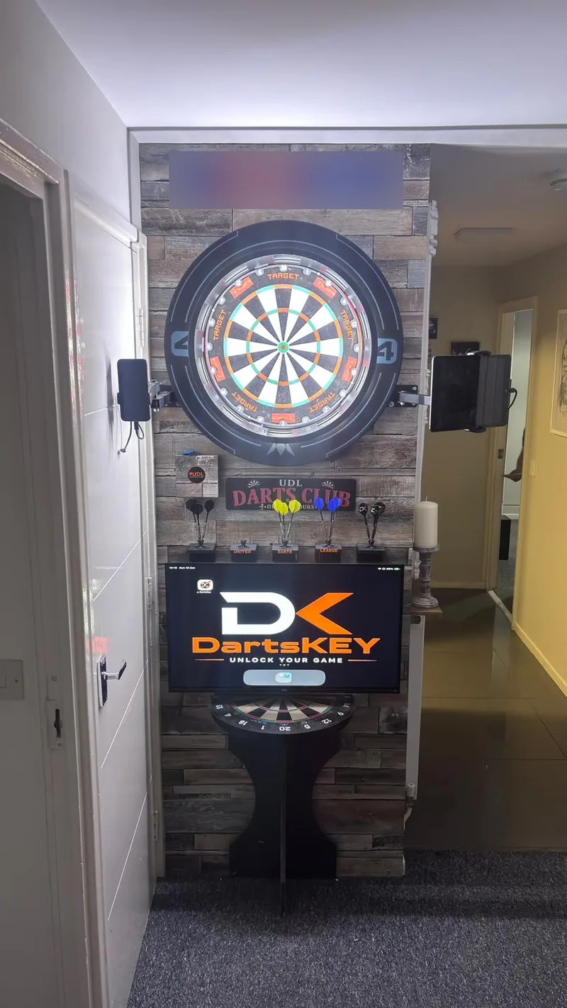 A dartboard set into a wood-panelled wall with the DartsKEY logo on a screen below it